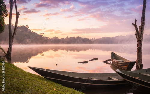 View of a wooden boats and big dry tree growing on Lake Nyabikere, with and the reflections on the water at sunrise, Rweteera, Fort Portal, Uganda, Africa photo