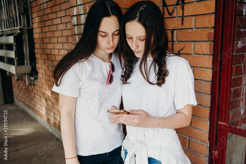 Teenage sisters looking at the mobile phone in the neighborhood