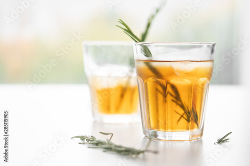 two glasses with lemonade and rosemary on a light background in high key