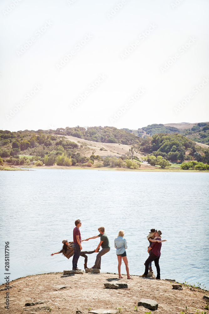 Group of friends hanging out in nature by lake Group of friends hanging out in nature by lake