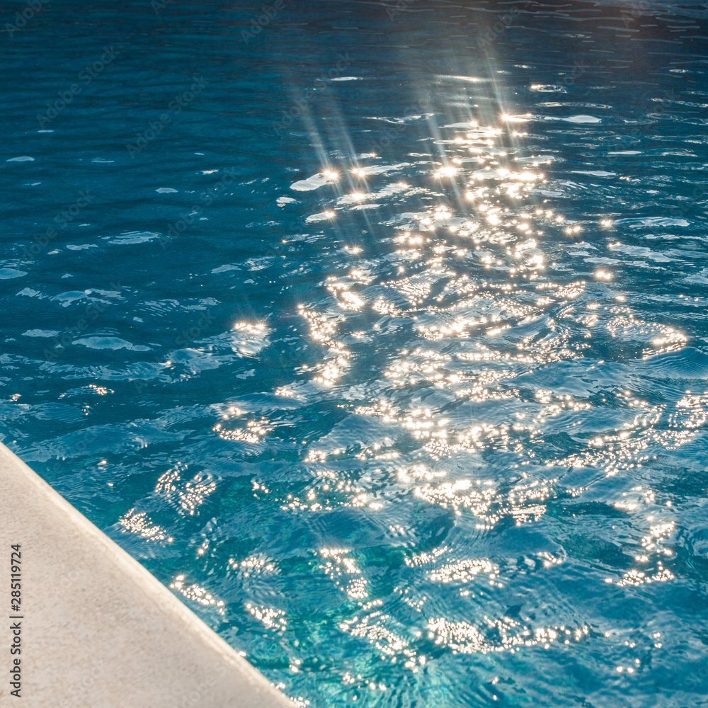 closeup of swimingpool with clean blue water and sun rays summer background