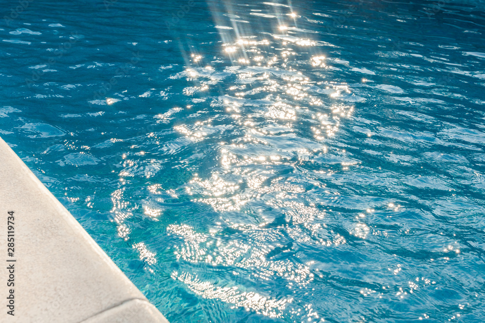 closeup of swimingpool with clean blue water and sun rays summer background