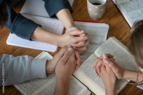 Christian worship and praise. Happy friends praying and reading the bible together. © PhotoGranary
