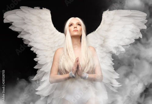 Fototapeta angel girl with white hair on black background, hands folded in prayer