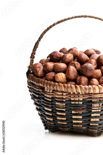 Small basket full of hazelnut kernels isolated on white