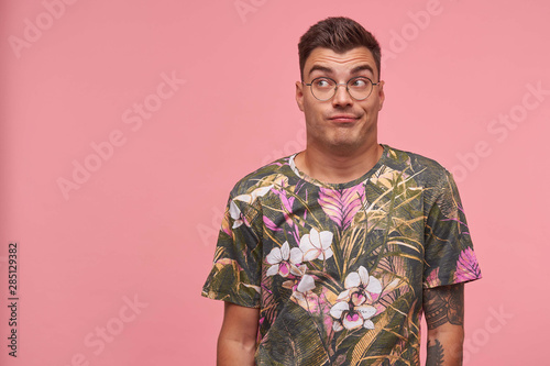 Wallpaper Mural Young attractive man standing in front camera over the pink background wih raised eyebrows, looking away, wearing glasses and printed t-shirt, seems bored and indifferent Torontodigital.ca