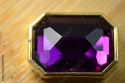 Isolated purple diamond with gold details on wooden background