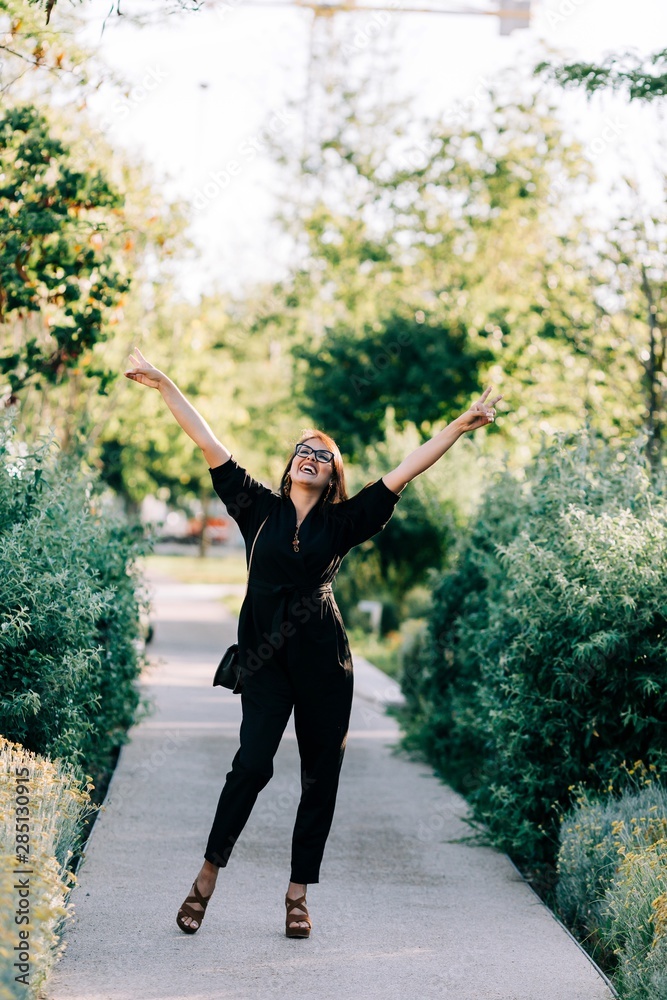 © Alexandra Coelho/ADDICTIVE STOCK - Trendy young woman in black suit walking along paved path and enjoying summer day in Lisbon