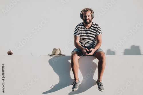 Young male sitting with smartphone and headphones photo