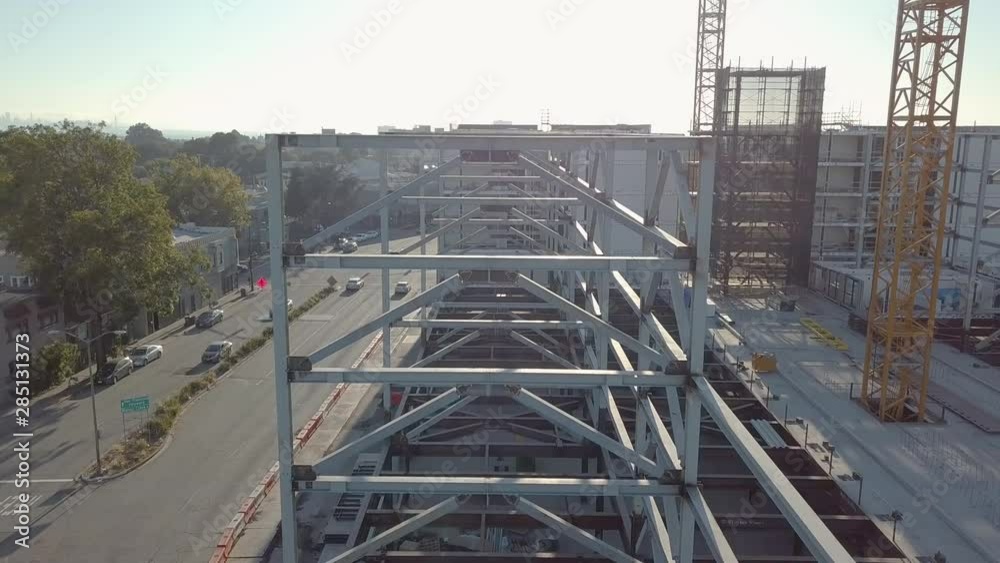 Steel frame of sustainable building under construction, Aerial crane down to ground floor, with lens flare. Steel frame of sustainable building under construction, Aerial crane down to ground floor, with lens flare.