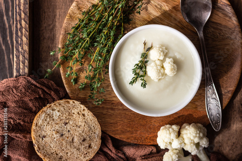 Wallpaper Mural Wooden tray with two ceramic bowl with cauliflower cream soup garnish with fresh cauliflower, thyme and bread