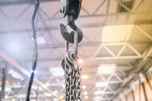 Industrial hook on a metal chain in a factory. Crane in the workshop for lifting heavy objects. Equipment for work at the enterprise