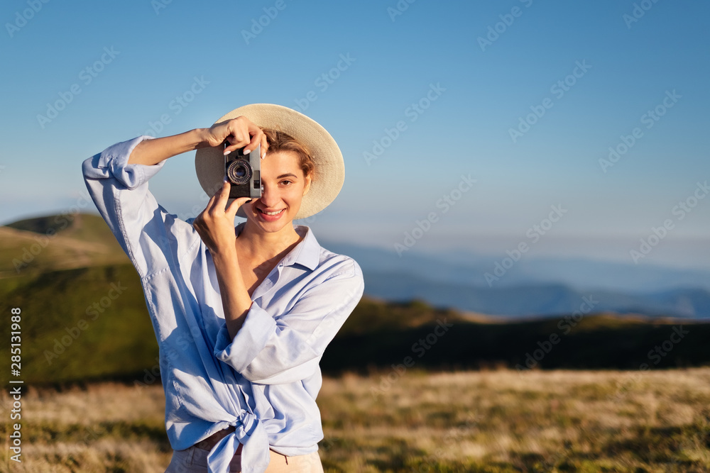 Young girl with a camera in the mountains during sunset. Girl and camera. Tourism and adventure. Photographing landscapes. Travel - Image Young girl with a camera in the mountains during sunset. Girl and camera. Tourism and adventure. Photographing landscapes. Travel - Image