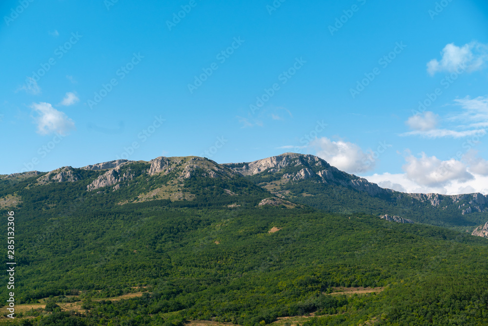 blue sky with clouds over green mountains