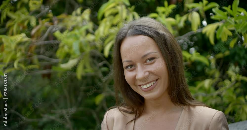 happy adult woman is smiling broadly and looking at camera outdoors in summer day happy adult woman is smiling broadly and looking at camera outdoors in summer day