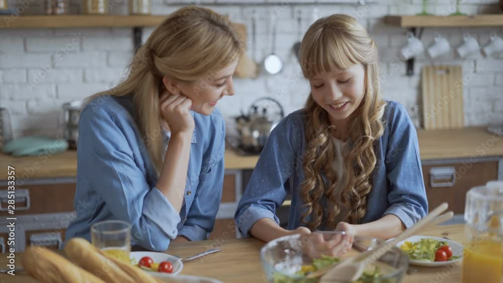 10 years old girl shows mom posts on a social network. Mom and daughter watch with a smartphone during lunch and have fun talking 4K 10 years old girl shows mom posts on a social network. Mom and daughter watch with a smartphone during lunch and have fun talking 4K