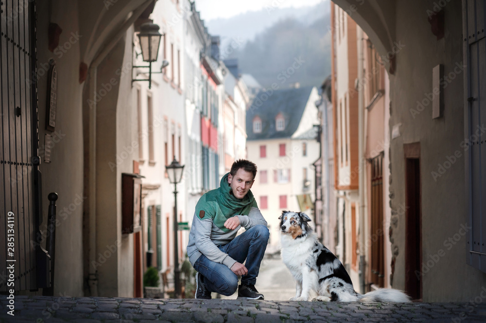 young man with a dog in the city. walk with a pet. Charming guy and Australian Shepherd young man with a dog in the city. walk with a pet. Charming guy and Australian Shepherd