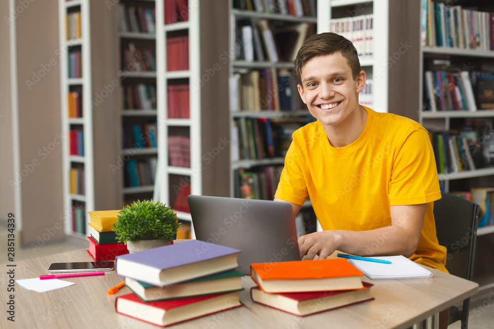 Happy intelligent student getting ready for exams in school library Happy intelligent student getting ready for exams in school library