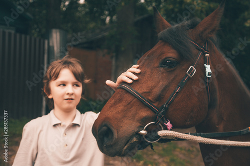 little child boy and his friend brown horse