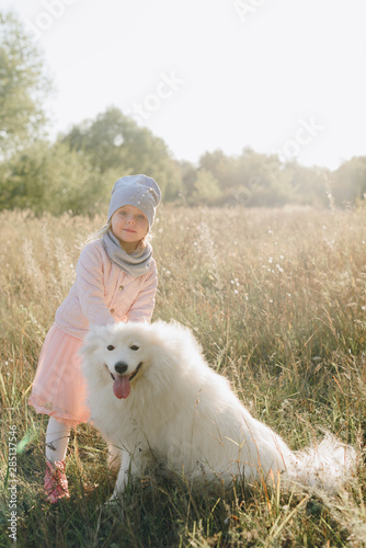 little girl with a big white dog in nature