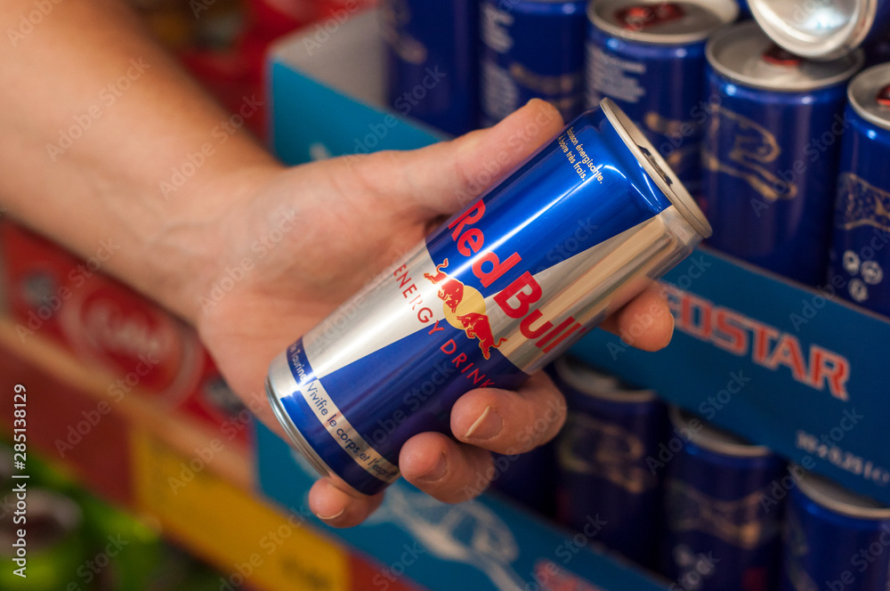 closeup of Red bull energy drink in aluminium can in hand at supermarket  Stock Photo | Adobe Stock
