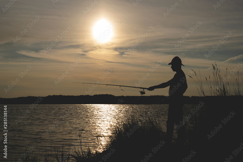 Fisherman silhouette with a rod on the pond.