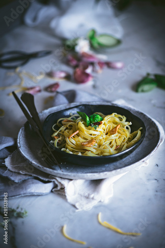 From above appetizing pasta with vegetables basil in black bowl on served table photo