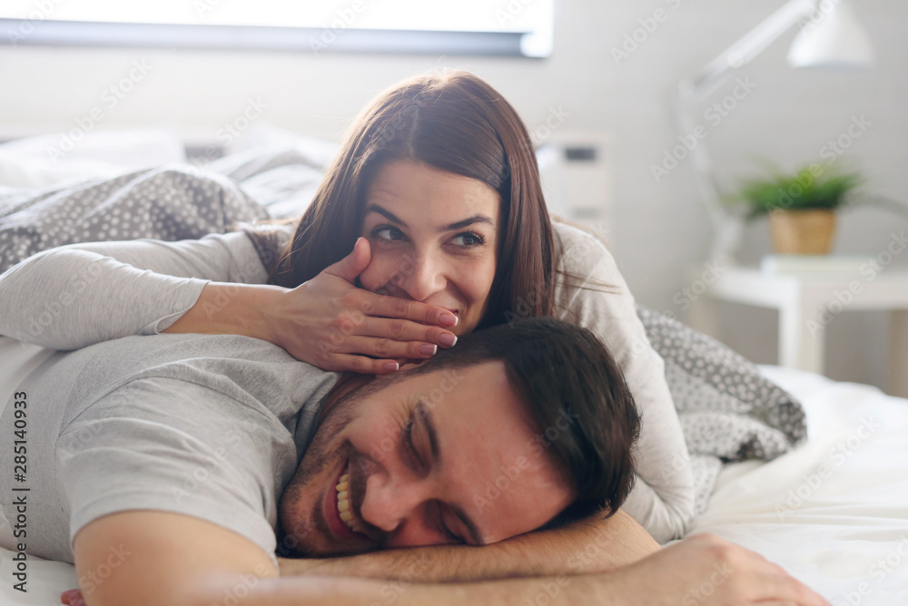 Obraz premium Young couple in love lying in bed. Intimate Couple Chatting in Bed about sex.