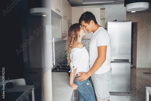 Loving couple have fun at home. Pretty blonde in a white blouse. Man and woman standing in a kitchen