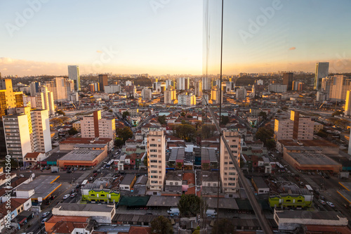 Fototapeta Naklejka Na Ścianę i Meble -  Aerial view of streets and avenues in Pinheiros neighborhood with commercial buildings and small houses at dusk on sunny summer day. The neighborhood has old houses and modern office buildings.