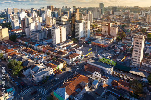 Aerial view of streets and avenues in Pinheiros neighborhood with commercial buildings and small houses at dusk on sunny summer day. The neighborhood has old houses and modern office buildings. photo