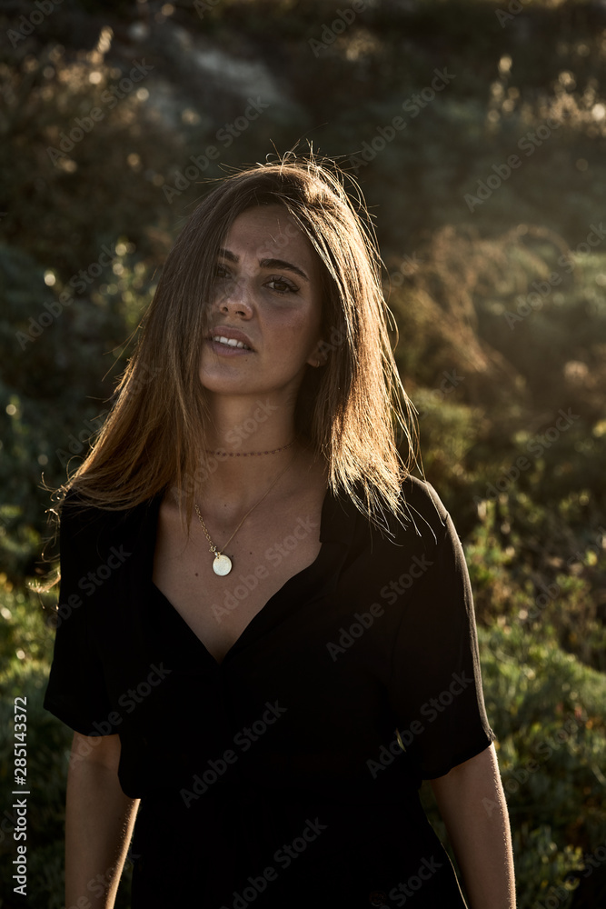 Young beautiful female model smiling and looking at camera in nature on sunny summer day Young beautiful female model smiling and looking at camera in nature on sunny summer day
