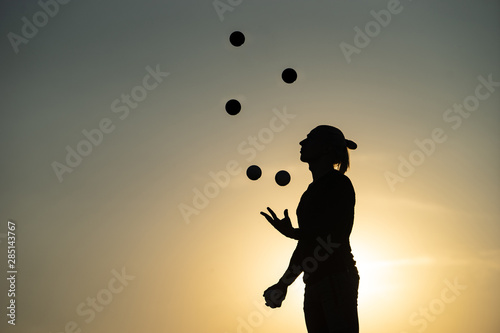 Silhouette of a man Juggling with Balls at Sunset photo