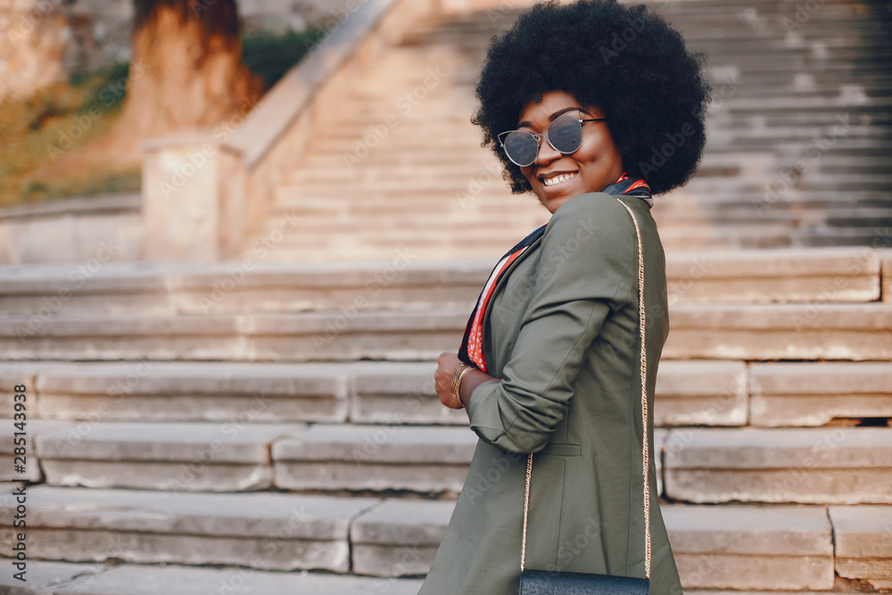 Fashionable girl in a summer city. Black lady in a green jacket. Woman in a red scarf. Famale with sunglasses Fashionable girl in a summer city. Black lady in a green jacket. Woman in a red scarf. Famale with sunglasses