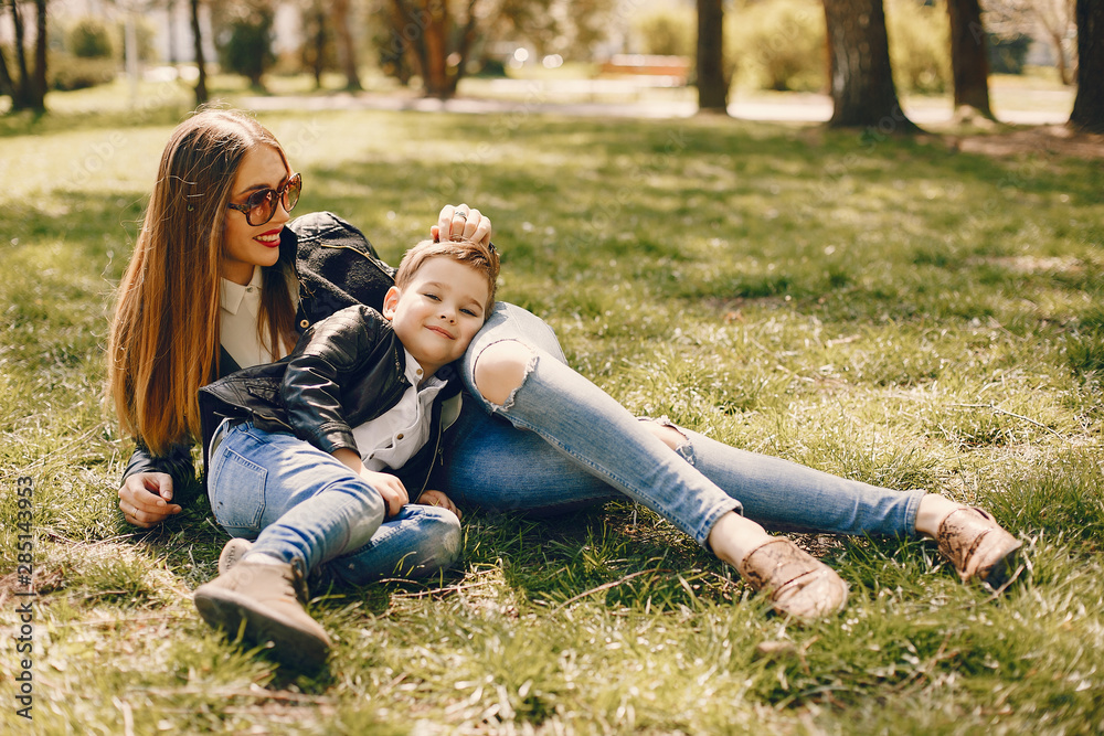 Family in a summer park. Mother in a black jacket. Cute little boy Family in a summer park. Mother in a black jacket. Cute little boy