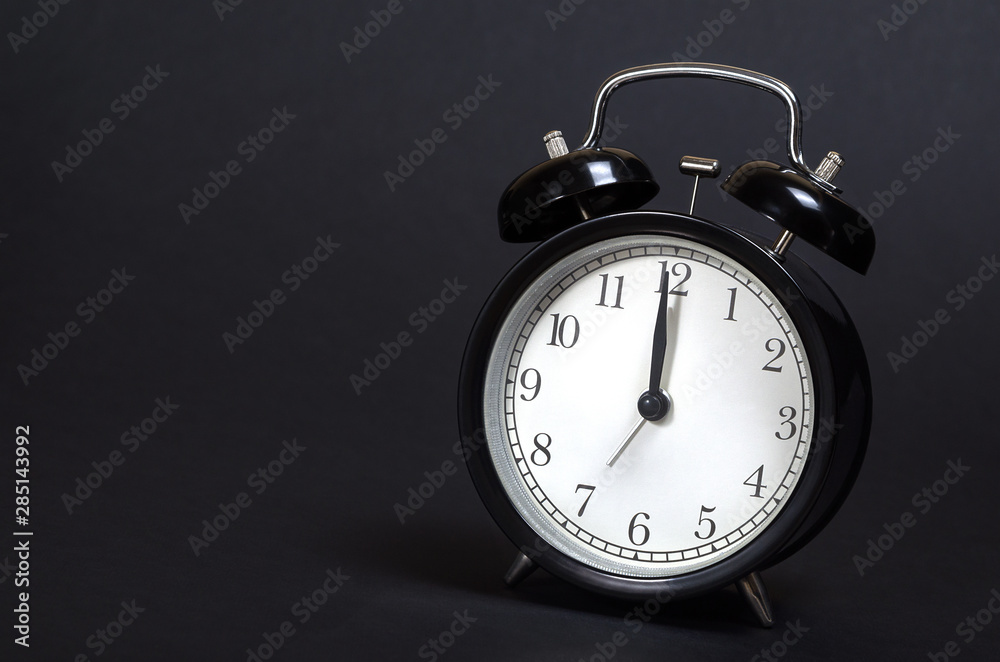 Time. Clock. Black retro alarm clock on blak background.