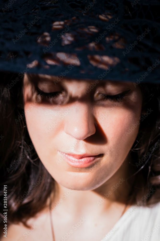 Beautiful woman in hat. Pretty young woman with a shadows pattern on face. Closed eyes