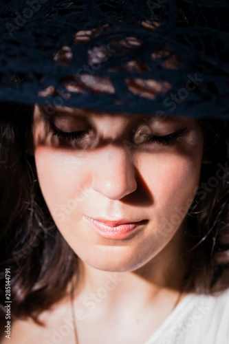 Beautiful woman in hat. Pretty young woman with a shadows pattern on face. Closed eyes