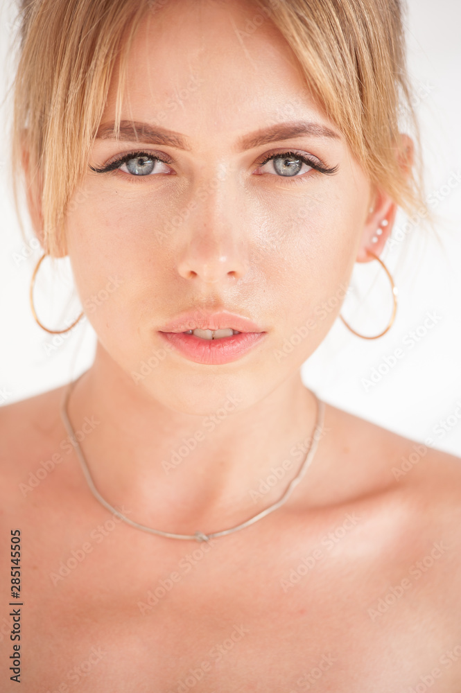 Portrait of young blonde woman on a white background in sunny day.
