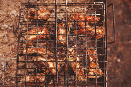 Frying meat over grill grid. Barbecue and cooking on the nature