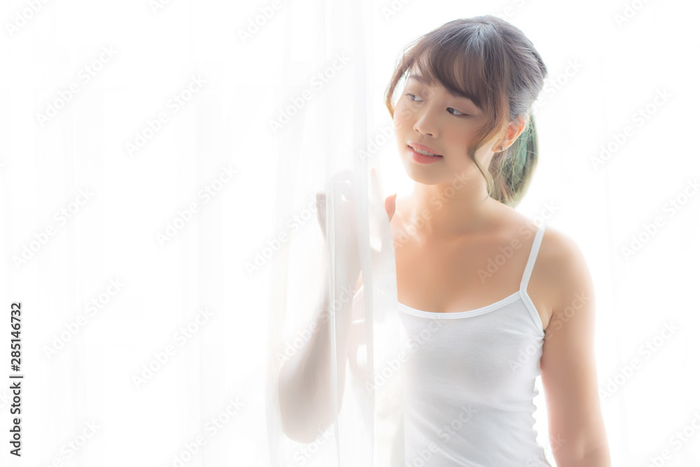 Portrait of beautiful young asian woman standing the window and smile while wake up with sunrise at morning, girl happy with freshness and cheerful, lifestyle and relax concept. Portrait of beautiful young asian woman standing the window and smile while wake up with sunrise at morning, girl happy with freshness and cheerful, lifestyle and relax concept.