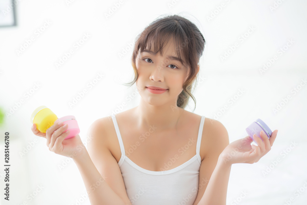 Beautiful portrait young asian woman holding and presenting cream or lotion product, beauty asia girl show cosmetic makeup and moisturizing for skin care, healthy care and wellness concept. Beautiful portrait young asian woman holding and presenting cream or lotion product, beauty asia girl show cosmetic makeup and moisturizing for skin care, healthy care and wellness concept.