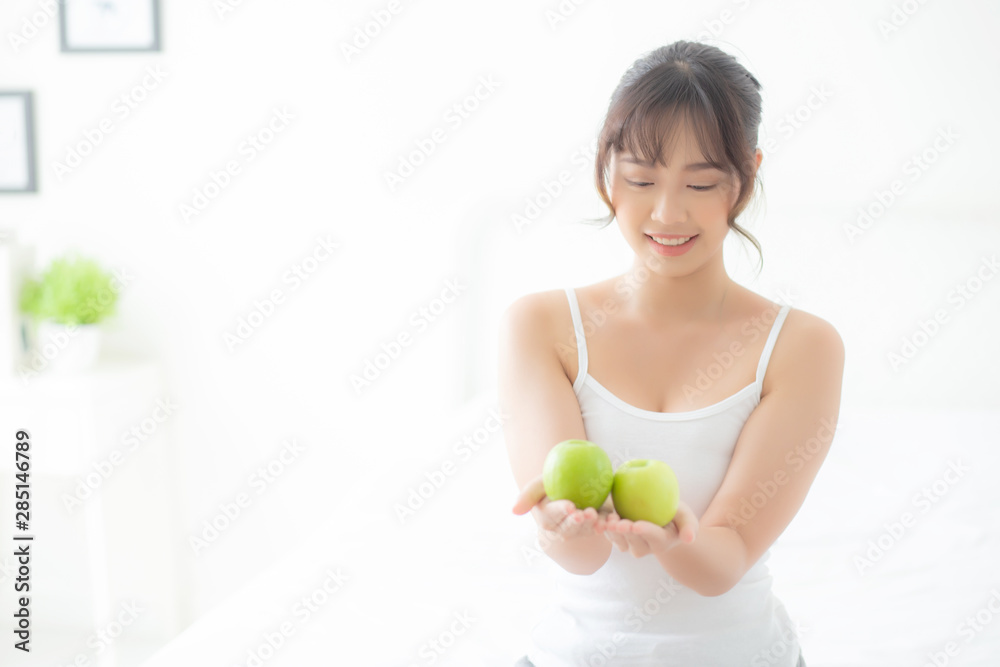 Beautiful portrait young asian woman holding and eating green apple fruit in the bedroom at home, lifestyle of nutrition girl healthy and care weight loss, health and wellness concept. Beautiful portrait young asian woman holding and eating green apple fruit in the bedroom at home, lifestyle of nutrition girl healthy and care weight loss, health and wellness concept.