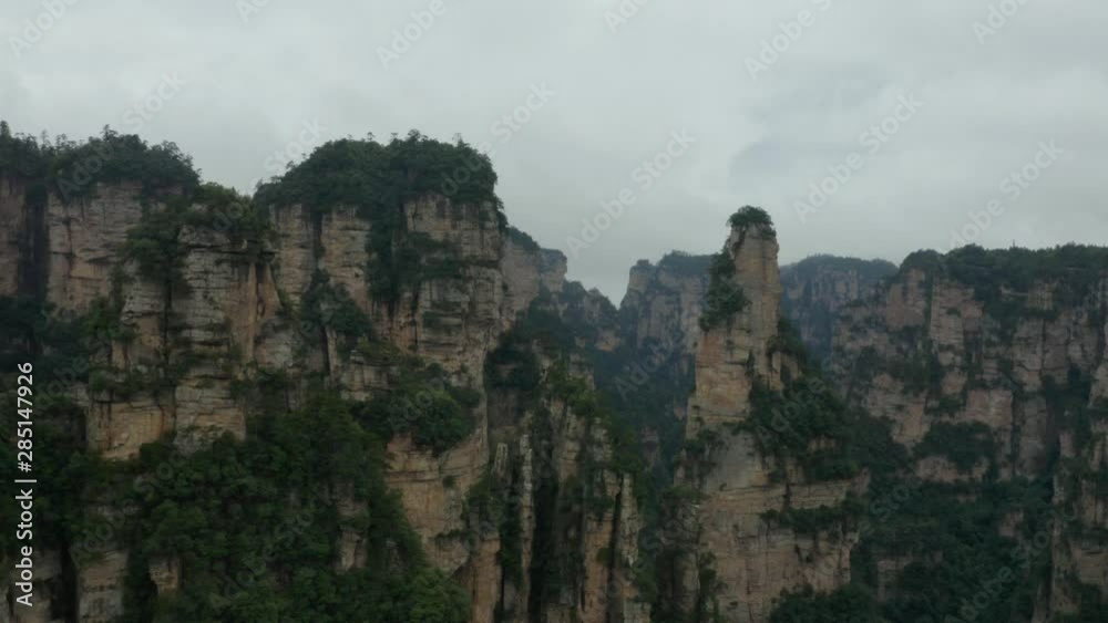 Aerial, rising, drone shot towards Avatar Hallelujah Mountain like quartz sandstone cliffs, in the Zhangjiajie national forest park, a UNESCO site, on a dark, moody day, in Hunan Province, China Aerial, rising, drone shot towards Avatar Hallelujah Mountain like quartz sandstone cliffs, in the Zhangjiajie national forest park, a UNESCO site, on a dark, moody day, in Hunan Province, China