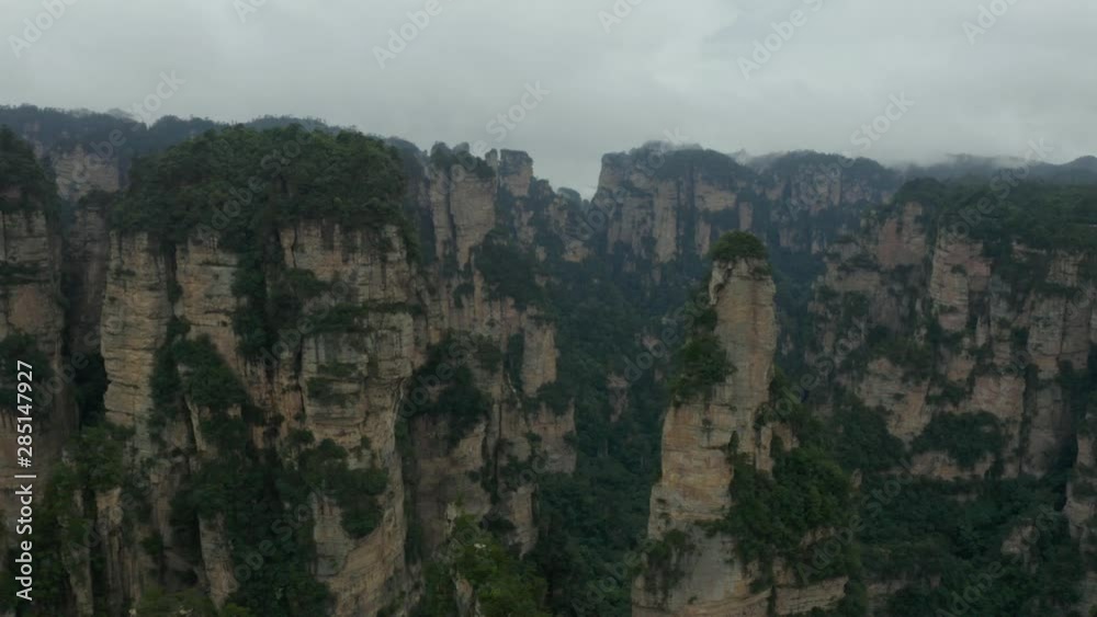 Aerial, rising, drone shot overlooking Avatar Hallelujah Mountain like quartz sandstone cliffs, in the Zhangjiajie national forest park, a UNESCO site, on a dark, moody day, in Hunan Province, China Aerial, rising, drone shot overlooking Avatar Hallelujah Mountain like quartz sandstone cliffs, in the Zhangjiajie national forest park, a UNESCO site, on a dark, moody day, in Hunan Province, China