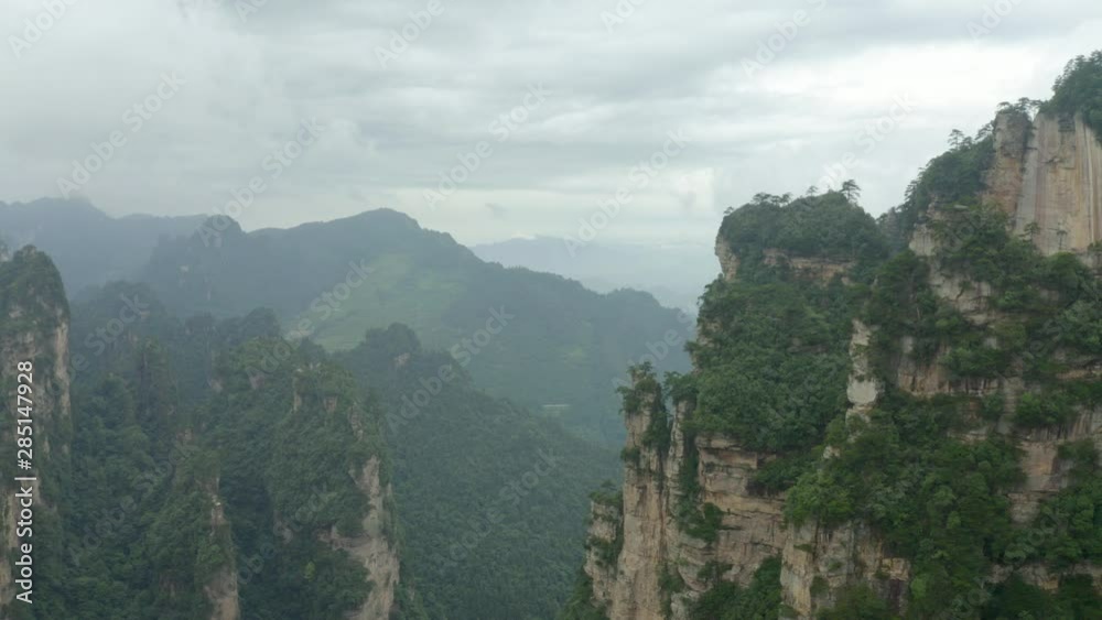 Aerial, drone shot towards Avatar Hallelujah Mountain like cliffs, in the Zhangjiajie national forest park, a UNESCO site, on a dark and moody day, in Hunan Province, China