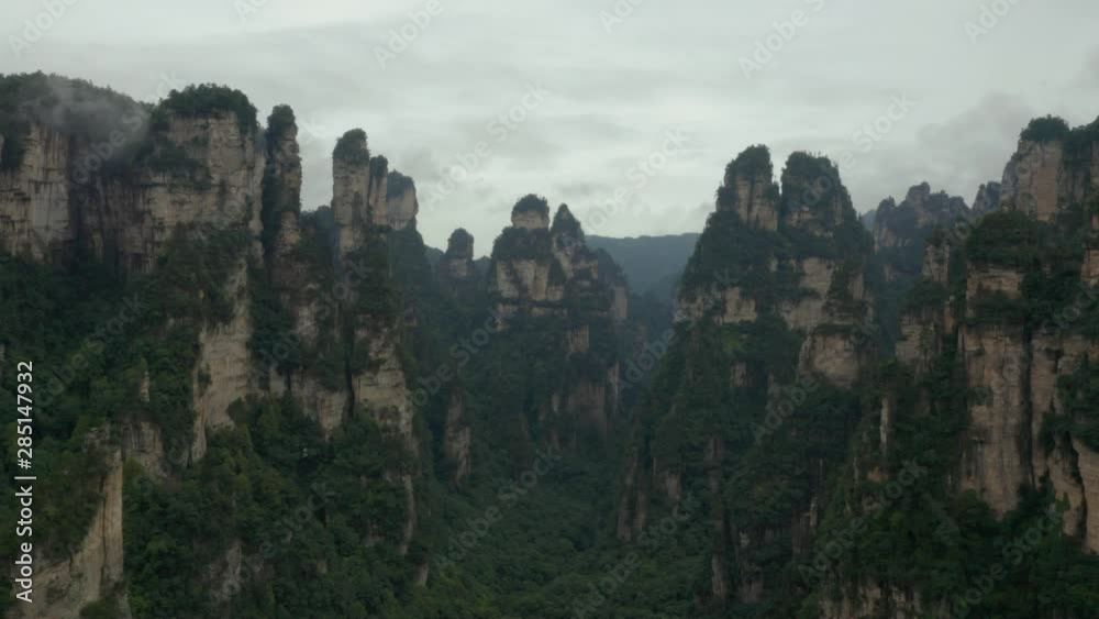 Aerial, drone shot, flying between quartz pillars, in the Zhangjiajie national forest park, at a UNESCO site, on a cloudy and foggy day, in Hunan Province, china Aerial, drone shot, flying between quartz pillars, in the Zhangjiajie national forest park, at a UNESCO site, on a cloudy and foggy day, in Hunan Province, china