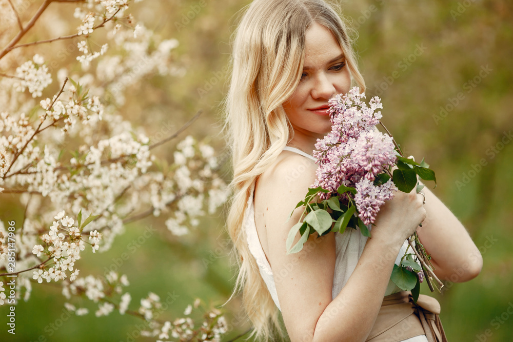 Fototapeta premium Beautiful girl in a white dress. Woman in a spring blooming park