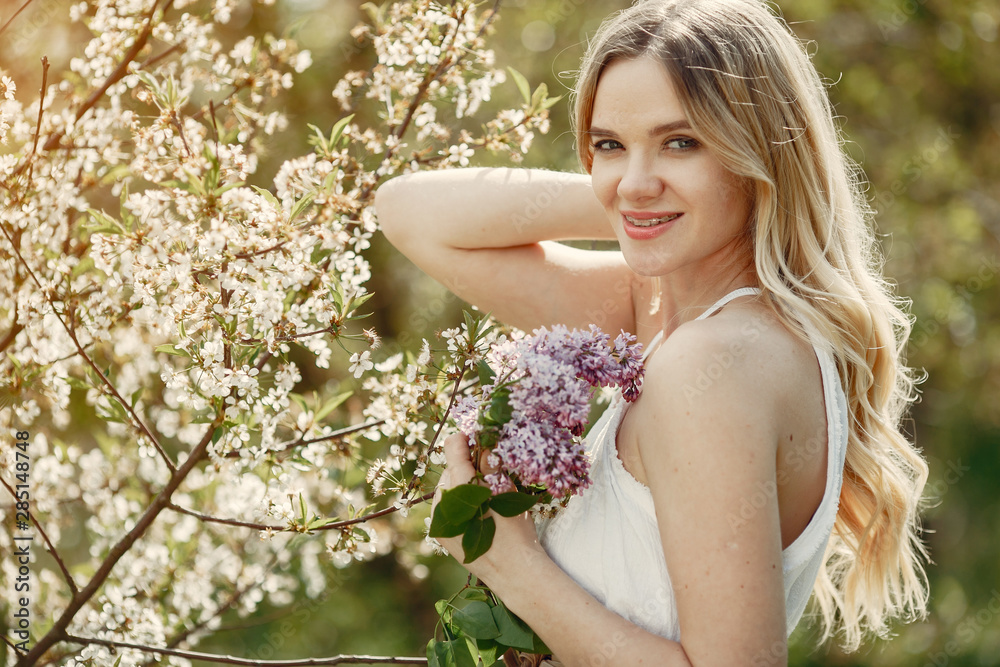 Beautiful girl in a white dress. Woman in a spring blooming park