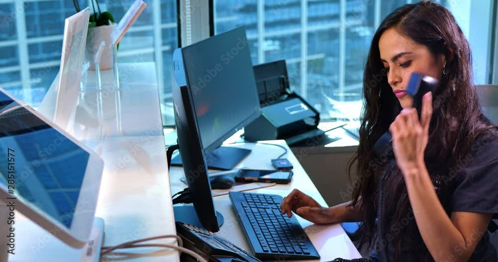 Medical office secretary talking on phone with patient using computer, 4K